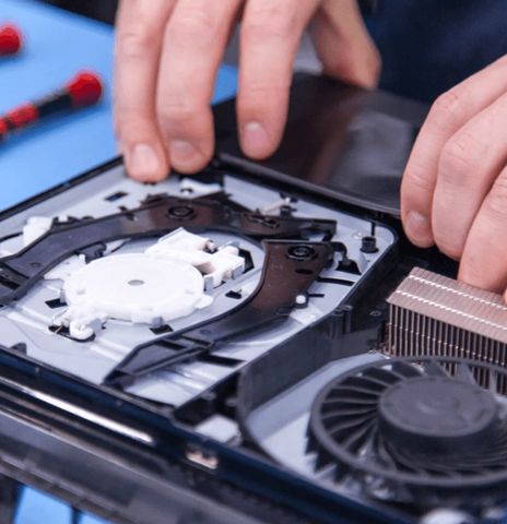 Games console opened on the bench with the cooling fan and heatsink exposed