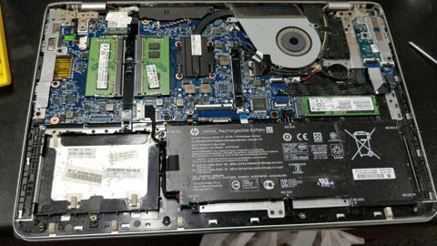 HP laptop opened up showing the memory, SSD and battery during a service