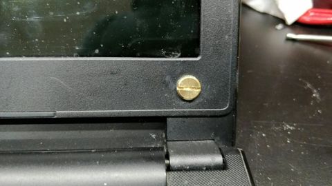 A repaired laptop hinge mount with a new screw fitted